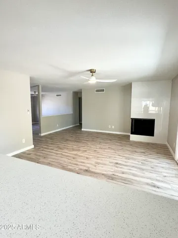 a view of empty room with wooden floor and fan