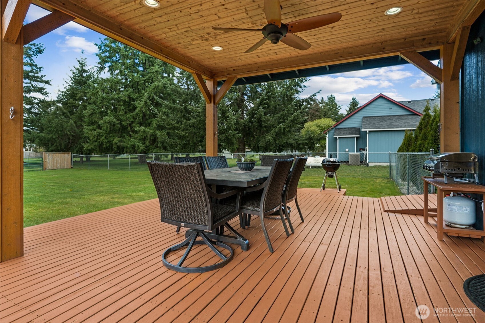 17837 Gilbert Street Southeast Tenino, WA 98589 - Photo 23 of 32 a view of a patio with table and chairs barbeque with wooden floor and fence