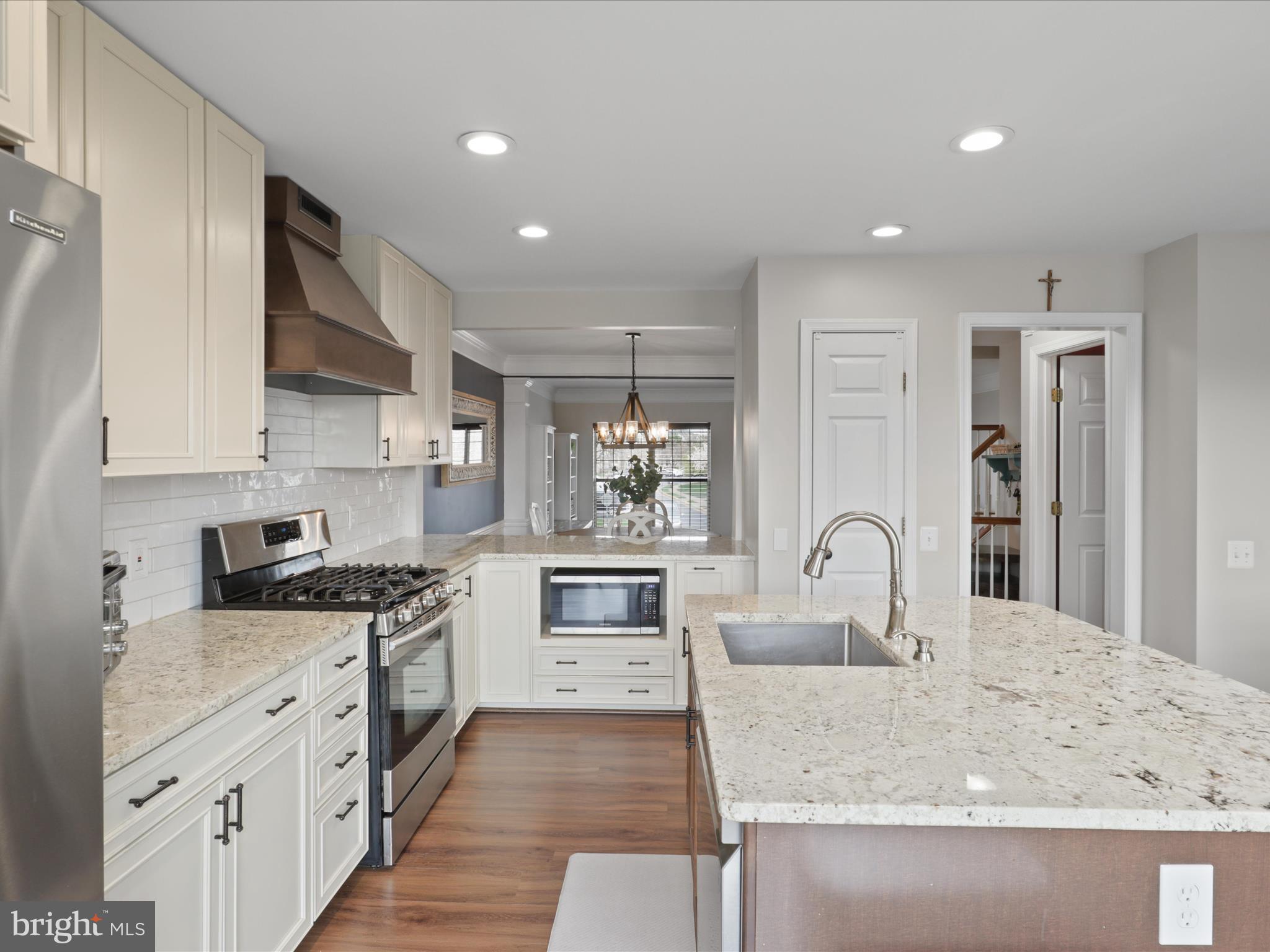 43271 Chokeberry Square Ashburn, VA 20147 - Photo 10 of 45 a kitchen with stainless steel appliances granite countertop a stove top oven a sink a refrigerator and white cabinets with wooden floor