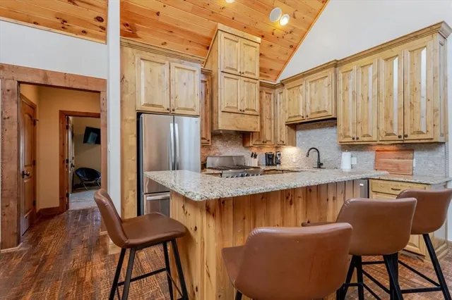 a kitchen with stainless steel appliances granite countertop a stove a refrigerator a sink dishwasher and wooden cabinets with wooden floor