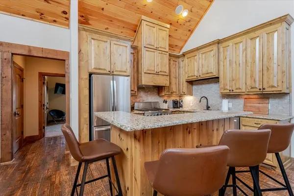 a kitchen with stainless steel appliances granite countertop a stove a refrigerator a sink dishwasher and wooden cabinets with wooden floor