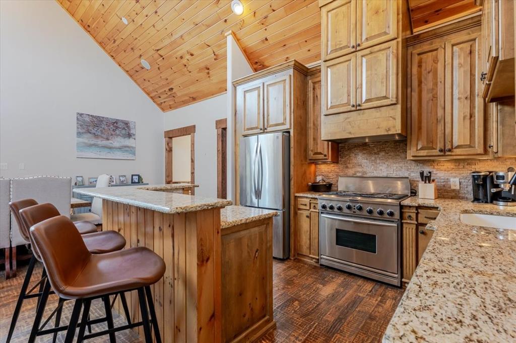 2034 Harbor Way, Unit 601 Graford, TX 76449 - Photo 10 of 27 a kitchen with stainless steel appliances granite countertop a stove a refrigerator a sink dishwasher and wooden cabinets with wooden floor