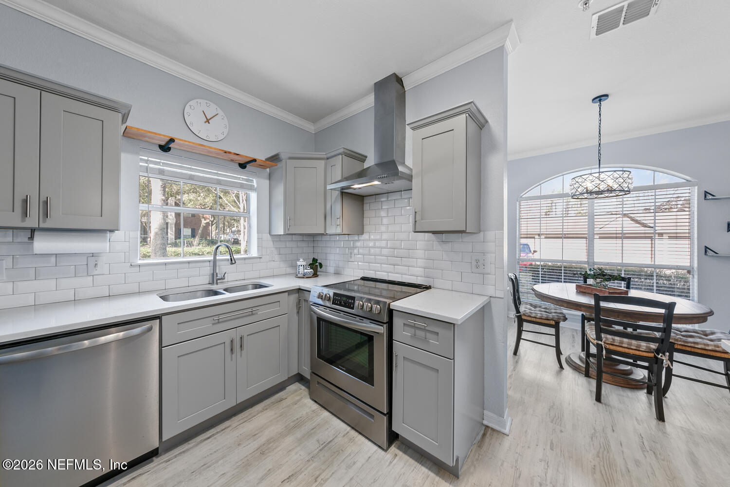 10961 Burnt Mill Road, Unit 317 Jacksonville, FL 32256 - Photo 11 of 39 a kitchen with stainless steel appliances a stove a sink dishwasher a dining table and chairs with wooden floor