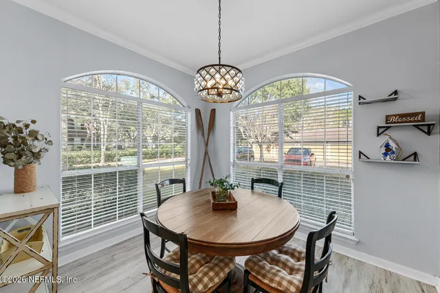 a dining room with wooden floor a chandelier a wooden table and chairs