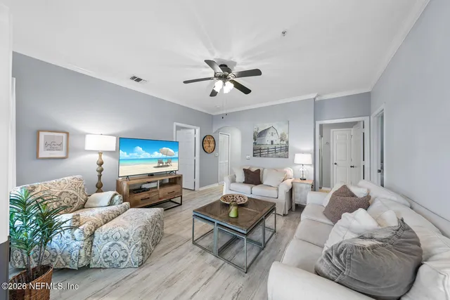 a living room with furniture a flat screen tv and a ceiling fan