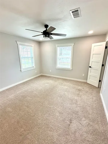 an empty room with windows and fan