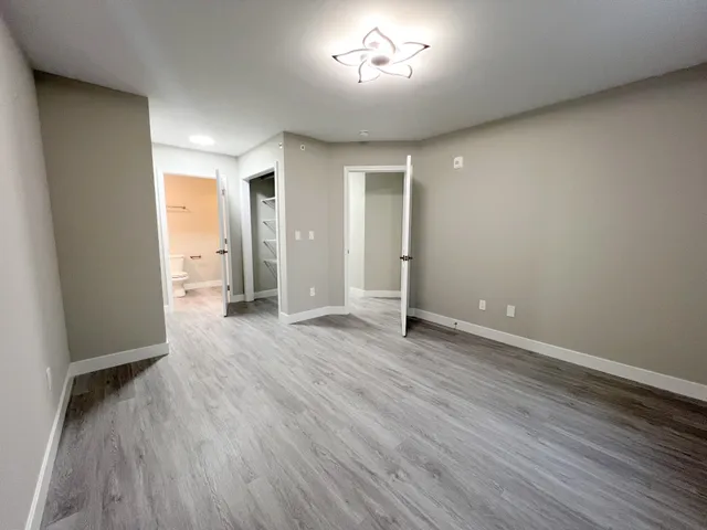 an empty room with wooden floor and windows