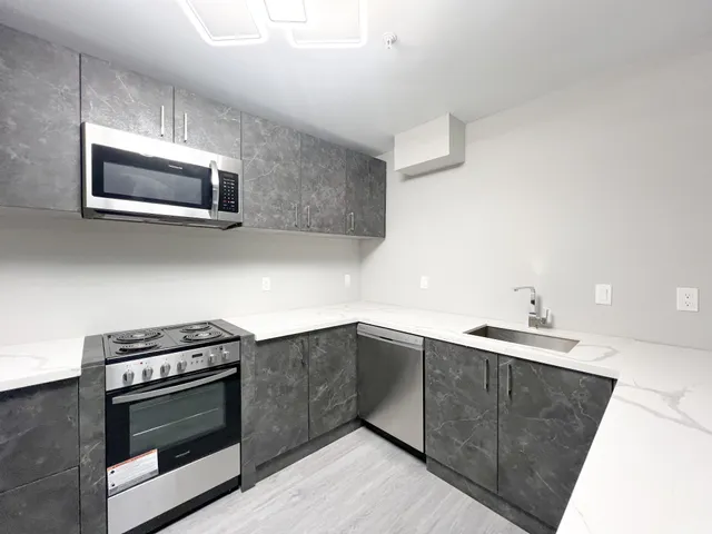 a kitchen with stainless steel appliances a stove microwave and sink