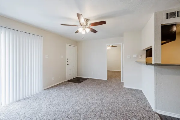 a view of an empty room with a window and a kitchen