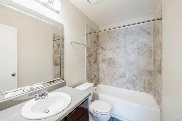 a bathroom with a bathtub shower sink vanity mirror and toilet