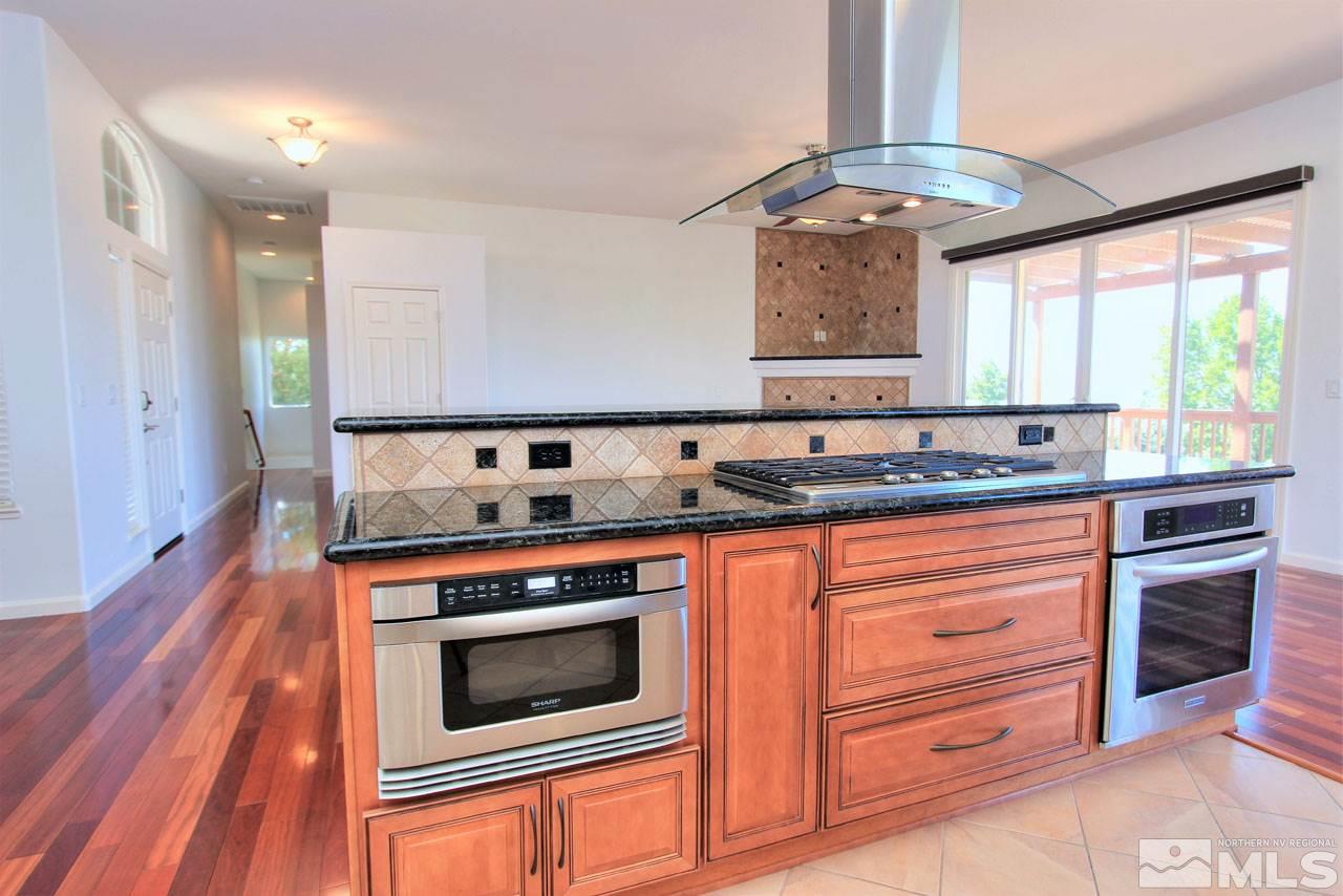 1094 University Ridge Drive Reno, NV 89512 - Photo 6 of 23 a kitchen with stainless steel appliances granite countertop a stove and a microwave