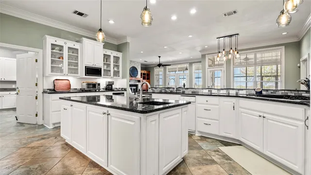 a kitchen with granite countertop a sink a counter space appliances and cabinets