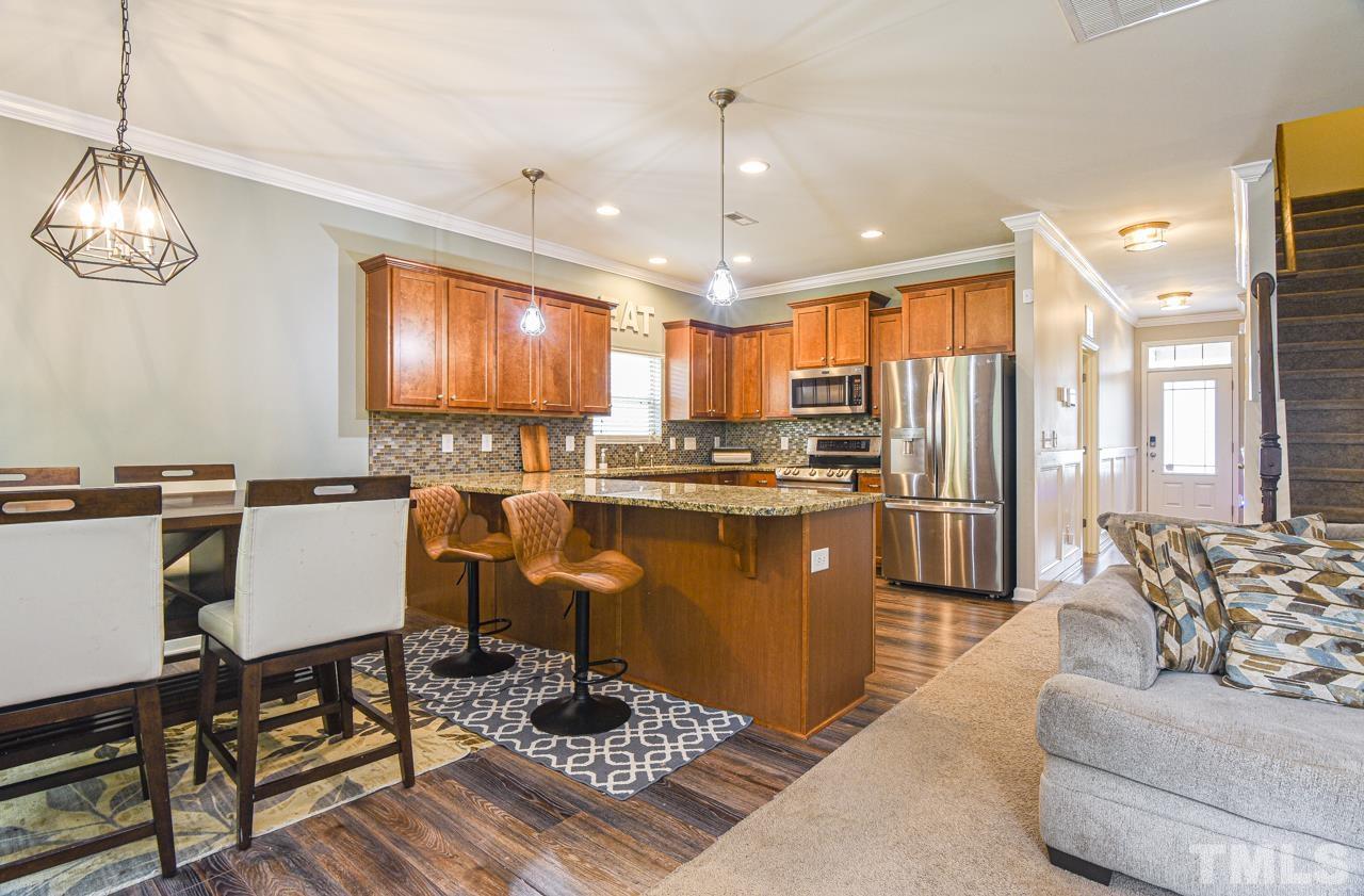 3644 Tule Spring Street Raleigh, NC 27610 - Photo 2 of 18 a kitchen with stainless steel appliances granite countertop a refrigerator a stove and a dining table with wooden floor