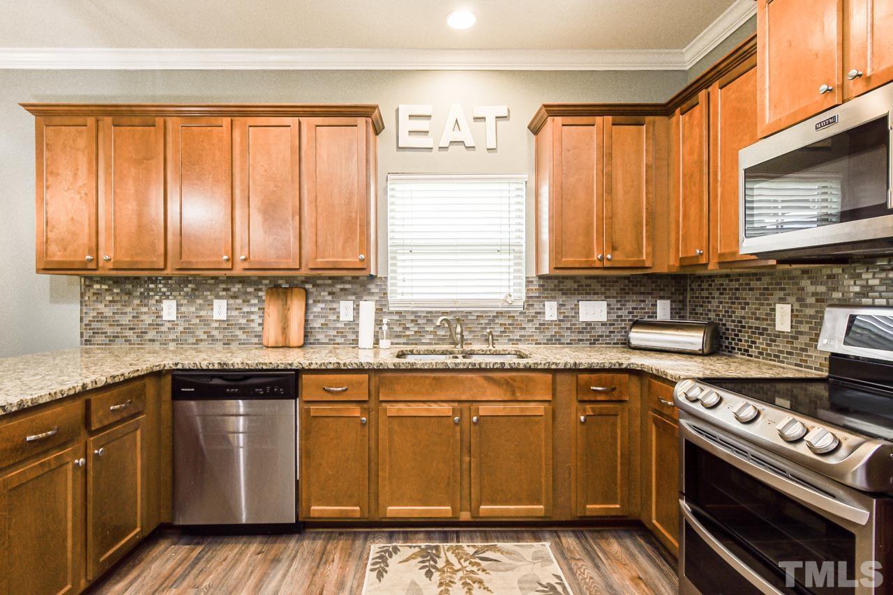 3644 Tule Spring Street Raleigh, NC 27610 - Photo 4 of 18 a kitchen with stainless steel appliances granite countertop a sink a stove a microwave cabinets and a window