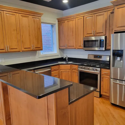 a kitchen with granite countertop wooden cabinets stainless steel appliances and a window