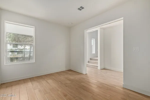 an empty room with wooden floor and windows
