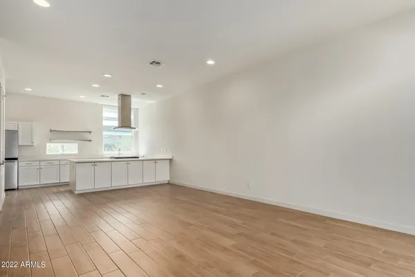 a kitchen with stainless steel appliances wooden floors and white walls
