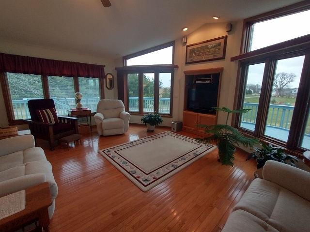 8597 East Winneshiek Road Ridott, IL 61067 - Photo 11 of 49 a living room with furniture floor to ceiling window and a flat screen tv