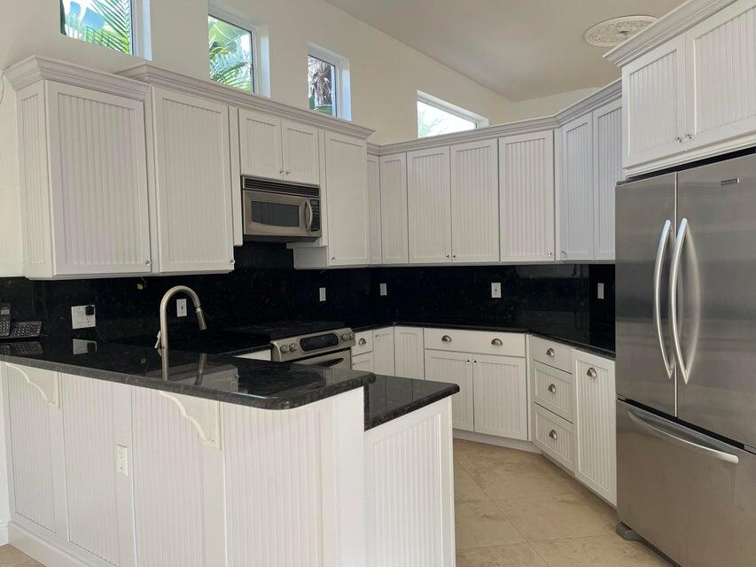 a kitchen with stainless steel appliances granite countertop a refrigerator a sink a stove and white cabinets