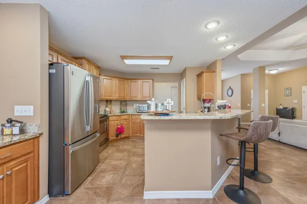 a kitchen with stainless steel appliances a refrigerator a stove a sink dishwasher and a dining table with wooden floor