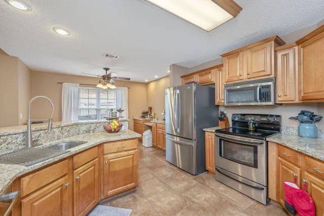 a kitchen with stainless steel appliances granite countertop a sink stove and refrigerator