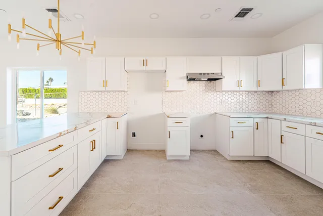a kitchen with white cabinets and window