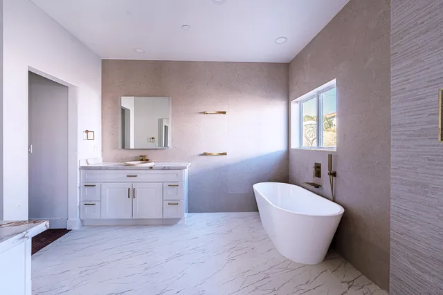 a spacious bathroom with a white tub a sink and a mirror