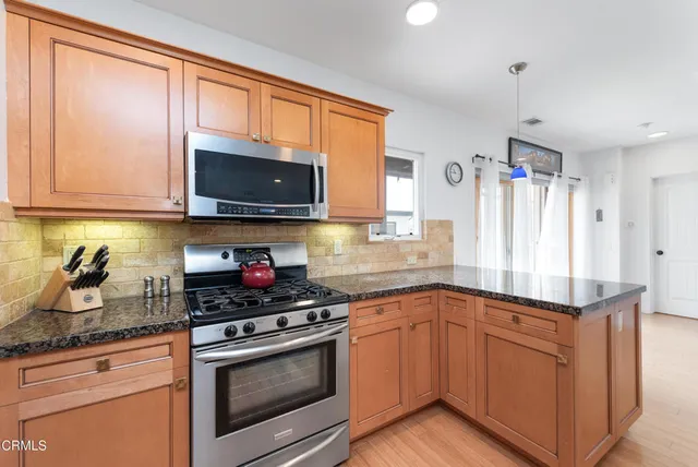 a kitchen with granite countertop cabinets stainless steel appliances and a window