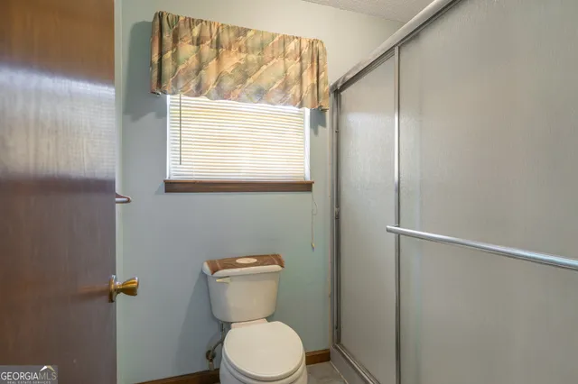 a white toilet sitting next to a window and a shower