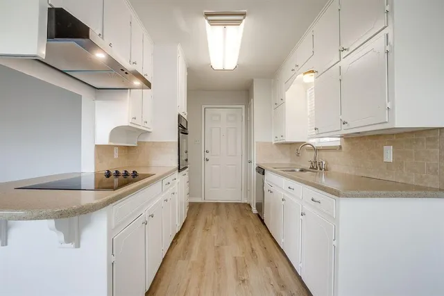 a kitchen with granite countertop a sink a stove refrigerator and cabinets