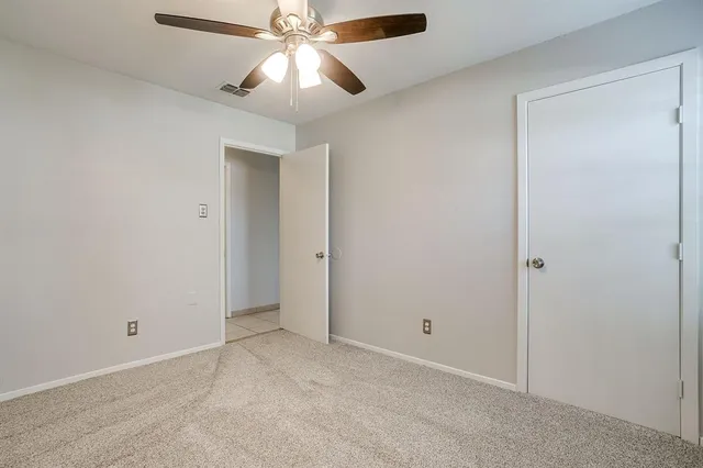 an empty room with closet and a chandelier fan
