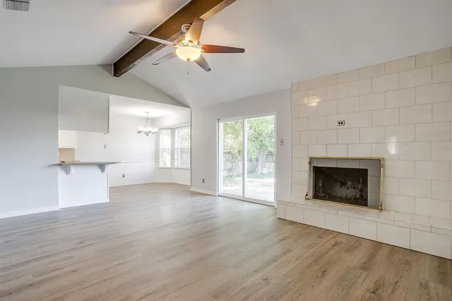 an empty room with wooden floor fireplace and windows