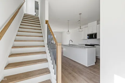 a kitchen with stainless steel appliances granite countertop a sink dishwasher a stove and a refrigerator with wooden floor