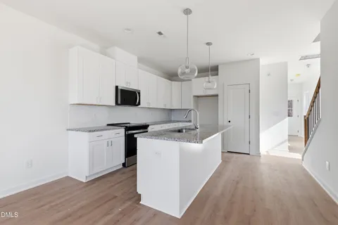 a kitchen with stainless steel appliances granite countertop a sink a stove and a wooden floors