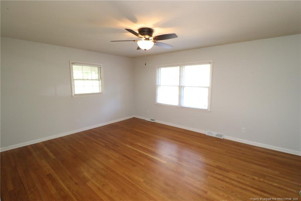 4909 Auburn Road Raleigh, NC 27609 - Photo 2 of 33 an empty room with wooden floor fan and windows