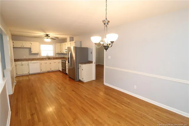 a view of a kitchen with stainless steel appliances wooden floor and a chandelier