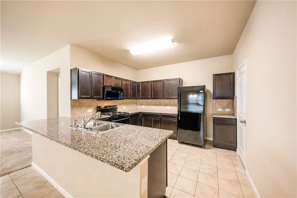 a kitchen with stainless steel appliances kitchen island granite countertop a refrigerator and a sink