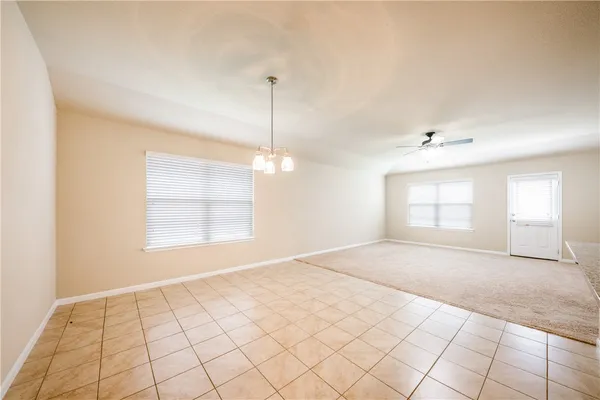 a view of an empty room and window and chandelier fan