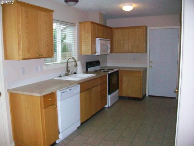1111 Southwest Ivory Loop Gresham, OR 97080 - Photo 4 of 8 a kitchen with a sink stove and cabinets