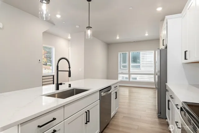 a kitchen with stainless steel appliances a sink a stove a refrigerator and cabinets