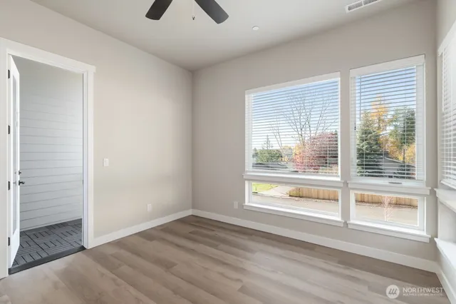 a view of an empty room with a window and wooden floor
