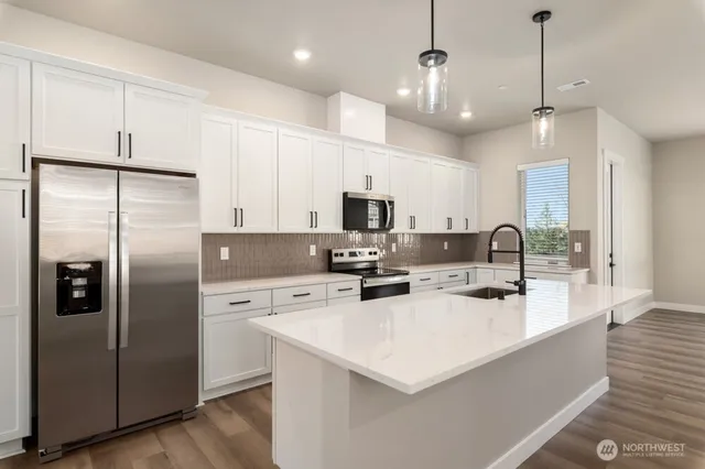 a kitchen with stainless steel appliances a refrigerator a sink a stove a oven and a center island