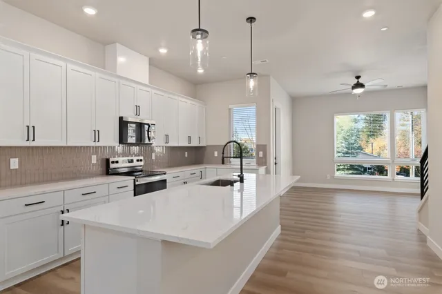 a large white kitchen with lots of counter space a sink appliances and cabinets