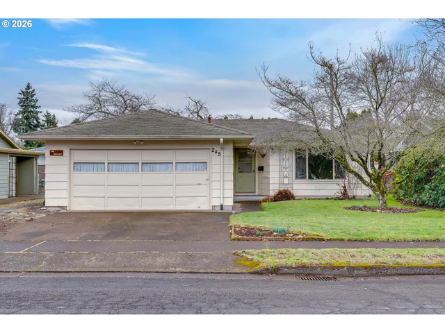 a view of a house with a yard and large tree