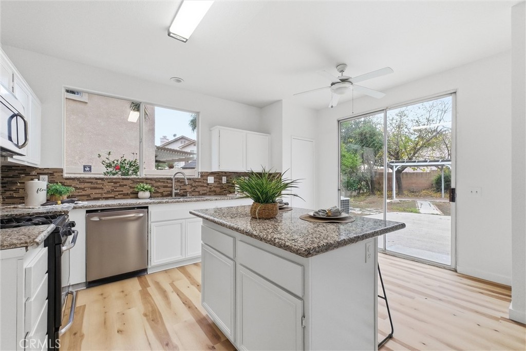 7522 Calais Court Rancho Cucamonga, CA 91730 - Photo 7 of 20 a kitchen with stainless steel appliances granite countertop a stove a sink and white cabinets with wooden floor