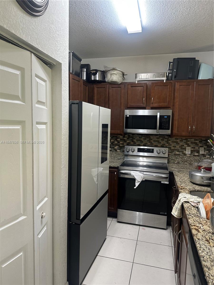 8922 Southwest 18th Street, Unit 8922 Miramar, FL 33025 - Photo 17 of 22 a kitchen with granite countertop a refrigerator and a stove top oven