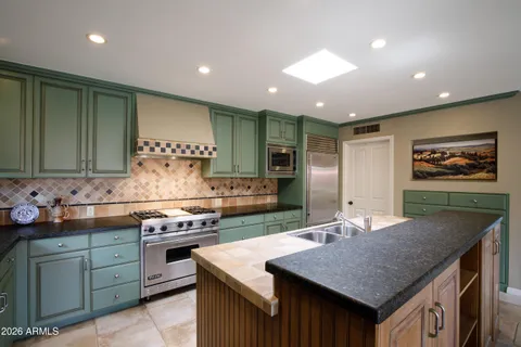 a dining hall with stainless steel appliances granite countertop a stove a sink a dining table and chairs with wooden floor
