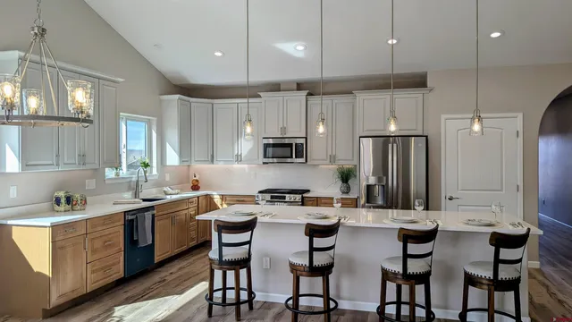 a kitchen with stainless steel appliances kitchen island granite countertop a table chairs microwave and sink