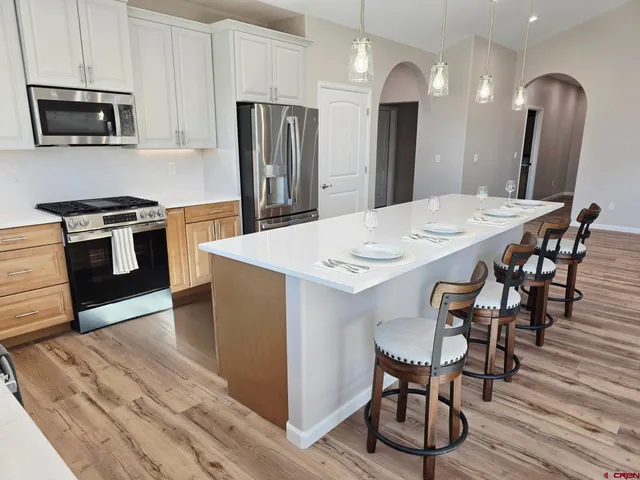 a large kitchen with stainless steel appliances kitchen island a table chairs in it and wooden floors