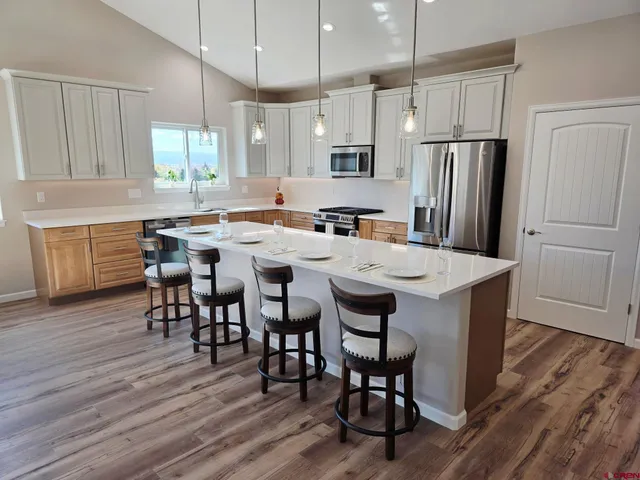 a kitchen with stainless steel appliances a dining table chairs stove refrigerator and cabinets